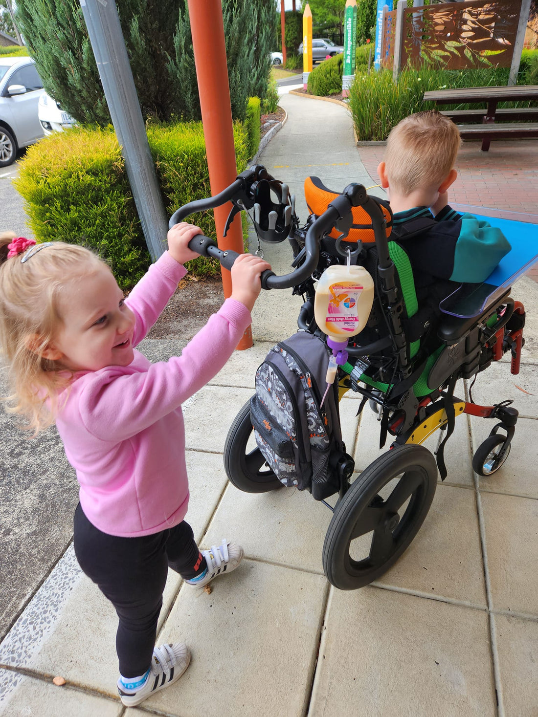 young sister pushing big brother in wheelchair