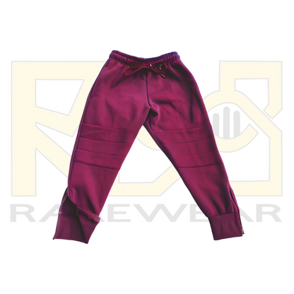 A pair of maroon OrthoEase Adaptive TrackPants for kids, featuring an elastic waistband with drawstring, double knee design, and ankle zips.