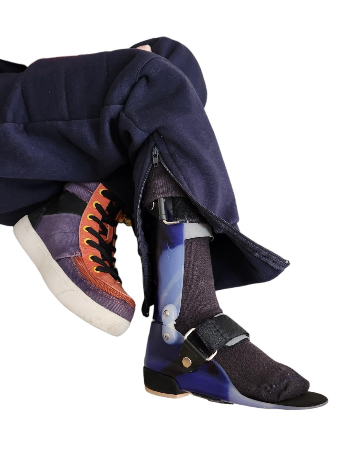 Close up of a pair of navy OrthoEase Adaptive TrackPants for kids, featuring an the zip with a Childs leg and AFO on